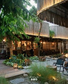 an outdoor area with chairs and lights in the evening time, surrounded by greenery