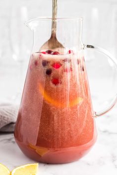 a pitcher filled with liquid next to sliced lemons