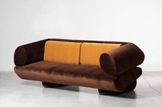 a brown and yellow couch sitting on top of a white floor next to a wall