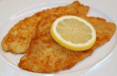 fried fish with lemon wedges on a white plate