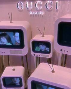 several televisions with faces on them in front of a gucci sign