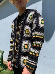 a man wearing a hat and sweater standing in front of a building