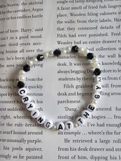 a beaded bracelet with words written in black and white beads on top of an open book