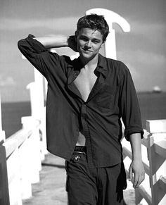 black and white photograph of a man standing on a pier with his shirt open in front of him