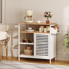 a small white cabinet in a living room next to a chair and table with flowers on it