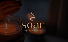 a person holding a candle with the word soar written on it in gold lettering