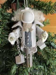 an ornament hanging from a christmas tree decorated with silver and white items,