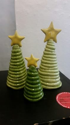 three small ceramic christmas trees with yellow stars on top, one is green and the other is white