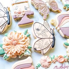 decorated cookies are arranged on a table with flowers and butterfly decorations in pastel colors