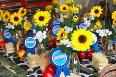 sunflowers and other flowers are arranged in vases on a table with straw bales