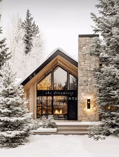 the exterior of a mountain lodge surrounded by snow covered trees