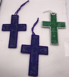 two cross shaped beads are sitting on a white cloth with blue and green beading