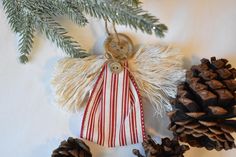 an angel ornament hanging from a christmas tree with pine cones on the side