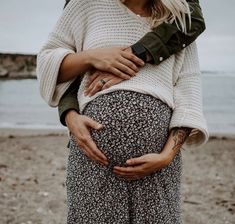 a pregnant woman holding her stomach on the beach