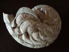 a piece of pottery sitting on top of a wooden table next to a black wall