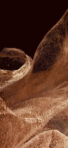 an abstract photograph of sand and water in brown tones with white dots on the edges