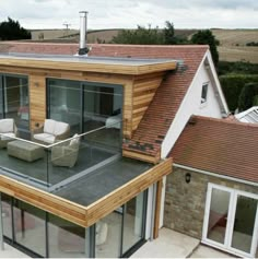 an aerial view of a modern house with glass walls and wood sidings on the roof