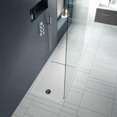 a bathroom with a walk in shower next to a white tiled floor and counter top