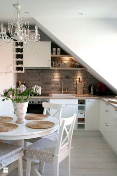 a white table with four chairs and a vase filled with flowers on top of it