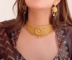 a close up of a woman wearing gold necklaces and matching earrings on her face