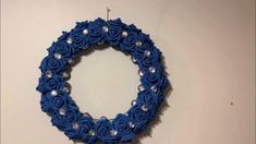 a blue wreath hanging on the wall with crystal beads and flowers in it's center