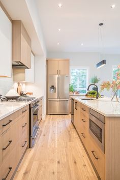 a modern kitchen with stainless steel appliances and wood flooring is pictured in this image