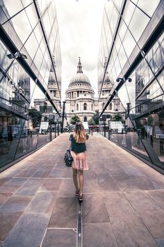 a woman is walking down the sidewalk in front of some glass buildings with domed domes