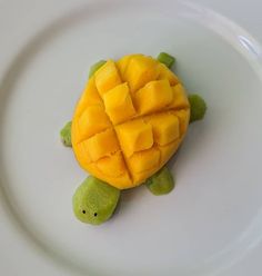 a small turtle made out of mango slices on a white plate with a green turtle in the middle