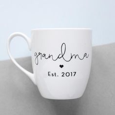 White mug with black grandma text Grandma Cups Vinyl, Coffee Mugs For Grandma, Grandma Coffee Mug Vinyl, Nana Coffee Mug, Corporate Holiday Gifts, Grandma Mug, Mother’s Day Coffee Mugs, New Grandma, Script Lettering