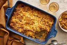 a blue casserole dish filled with food next to silverware