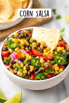 corn salsa in a white bowl with tortilla chips and cilantro on the side