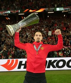 a man holding up a silver cup in front of a crowd at a soccer game