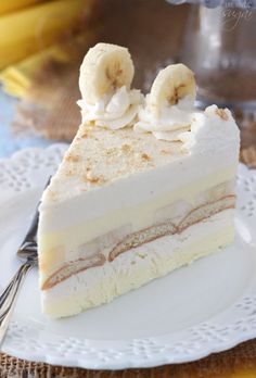 a piece of cake on a white plate with bananas in the middle and frosting