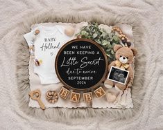 a baby announcement with teddy bears and other items on a fur blanket next to the words, we have been keeping a little secret