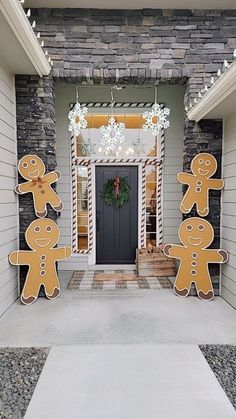 two large gingerbread cutouts are standing in front of a door with snowflakes hanging from it