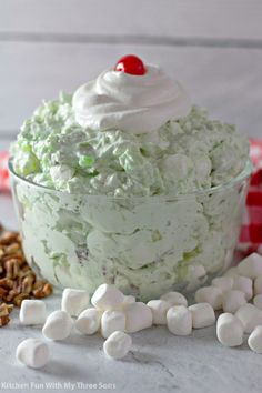 a dessert with marshmallows and whipped cream in a glass bowl next to pecans