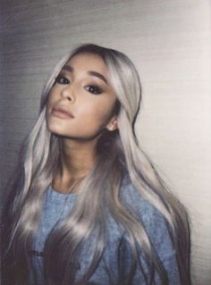 a woman with long grey hair is posing for a photo in front of a wall