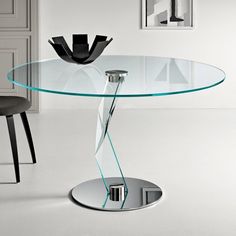 a glass table with a metal base in a white room next to a black chair