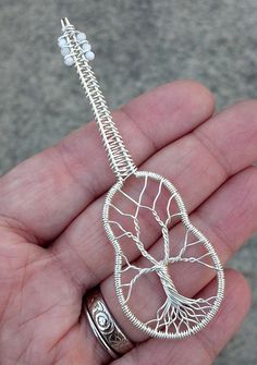 a hand holding a silver tree of life pendant