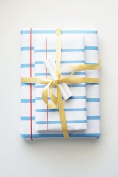 folded gift wrapped in white and blue striped paper with yellow ribbon tied around the edge