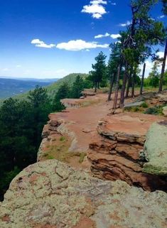 a rocky cliff with trees on the side and blue sky in the backgroud