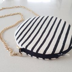 a black and white striped coin purse on a gold plated chain, sitting on a table