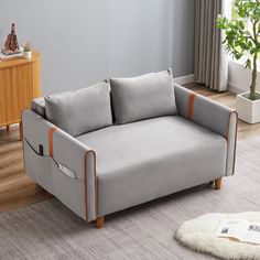 a gray couch sitting on top of a wooden floor next to a white rug and table