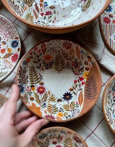 a hand is reaching for a bowl on a table with other plates and bowls around it