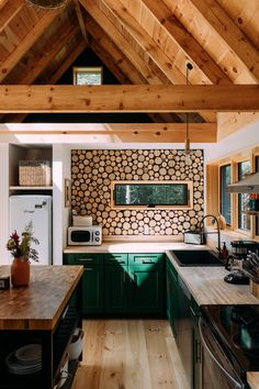 a kitchen with green cabinets and wood floors in the middle of an open floor plan