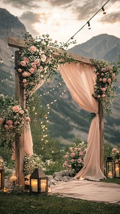 Elegant outdoor wedding decor for a mountain ceremony. Soft, flowing fabrics in blush and ivory, rustic wooden arches adorned with wildflowers. Cozy lanterns and fairy lights create a romantic ambiance. Captured with a Canon EOS R5 and a RF 50mm f/1.2 lens at sunset, highlighting the stunning backdrop and delicate details. Outdoor Spring Wedding Ideas Romantic Table Settings, Wedding Themes Nature, Elegant Farm Wedding Ideas, Sunset Mountain Wedding, Western Wedding Spring, Cottage Wedding Aesthetic, Cottage Core Wedding Decor, Woods Themed Wedding, Rustic Wedding Table Ideas