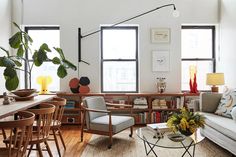 a living room filled with furniture and lots of windows next to a wooden dining table