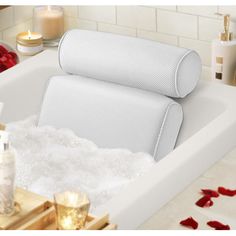 a white bath tub filled with foam next to candles and other bathroom items on the counter