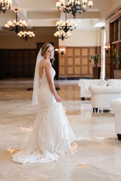 a woman in a wedding dress is posing for a photo at the reception room with chandeliers