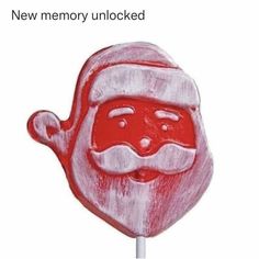 a red and white drawing of a santa claus face on a lollipop with the caption new memory unlocked